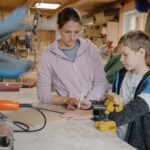 Bild von einer Frau und einem Jungen die bei einer Werkbank stehen und mit einem Bleistift Holz markieren