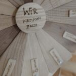 Bild von einem Holz Glücksrad auf dem in der Mitte steht 'Wir kemman zaum'