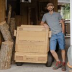 Ein Portrait von Klaus Pointecker der sich auf Konrad dem Holz LKW abstüzt