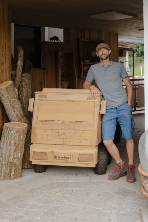 Ein Portrait von Klaus Pointecker der sich auf Konrad dem Holz LKW abstüzt