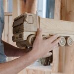 Ein kleiner Spielzeug LKW aus Holz gefertigt in den Händen von Klaus Pointecker